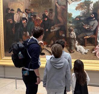 the tour guide show the details of a painting to the kids