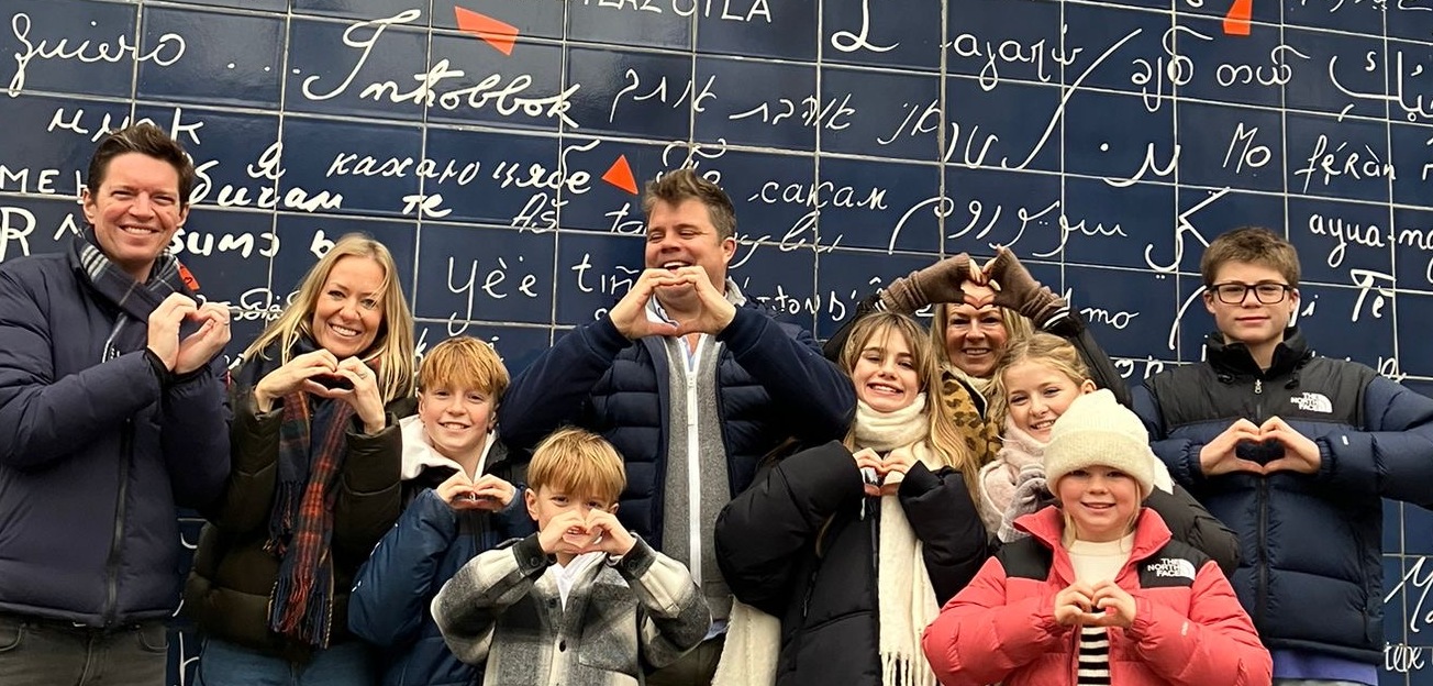 a family in front of the wall of love in montmartre paris making hearts with their hands