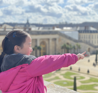 a young girl pointing finger in the gardens of Versailles 