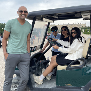 its a family waiting for you to get on a golf cart in the gardens of Versailles