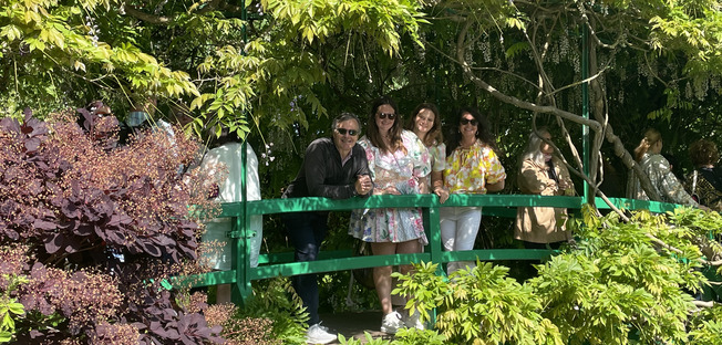 a family enjoying the bridge of the monet's garden with a beautiful sun and light and wisteria