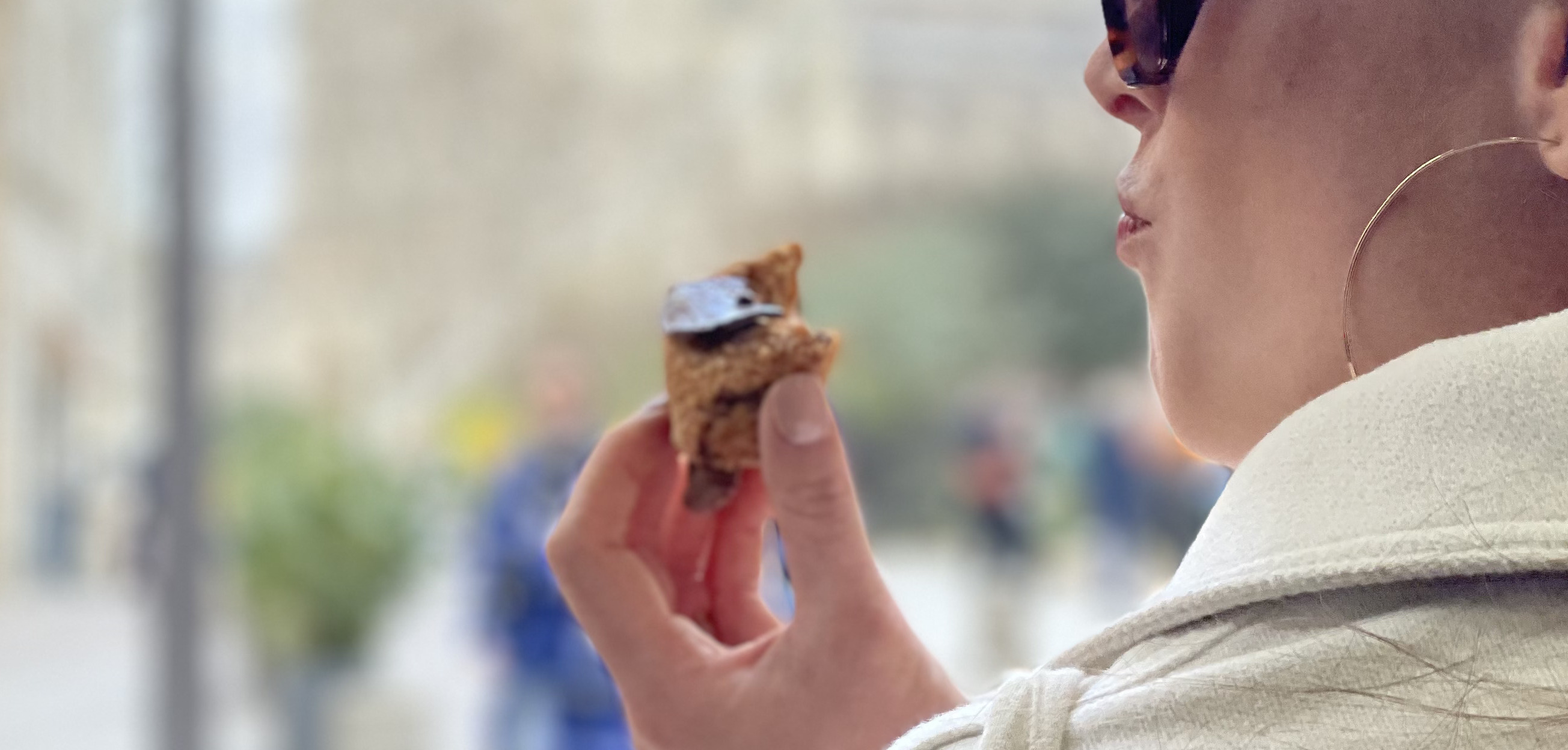 a lady eating an odette cream puff in front of Notre dame 