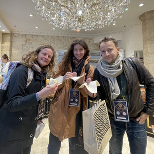 three guides having a bite at le merveilleux de fred there is a beautiful chandelier in the picture above the three characters and they a sweet treat